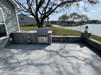 Outdoor patio with built-in grill, stone walls, and lake view.