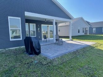 Backyard patio with a covered porch and grill on a sunny day.