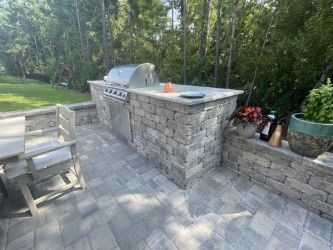 Outdoor kitchen with gray brick construction, built-in grill, and patio seating.