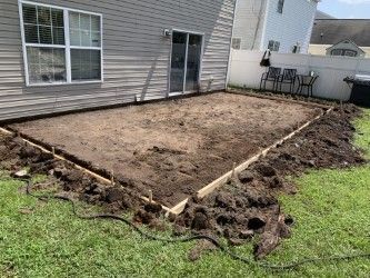 Backyard patio under construction with wooden frame, dirt, and a sliding glass door.