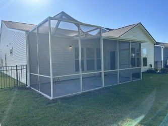 Screened-in porch attached to a light-colored house, with white framing and gray concrete flooring.