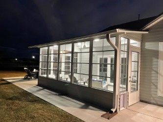 Screened porch with windows attached to a house; dark sky background.