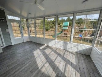 Sunroom with gray tiled floor, windows, and view of a playground.