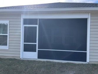 Screened-in porch with a white frame and black screen; beige siding of a house in background.