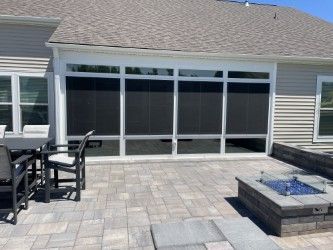 Patio with black screens, stone pavers, fire pit, and outdoor furniture.