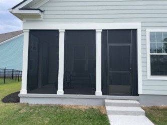 Screened porch with white columns, black screens, and door. Steps lead up to the porch. House exterior.