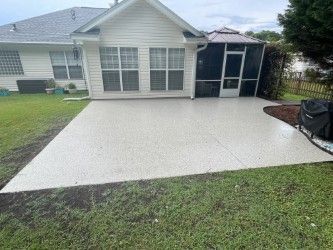 Concrete patio outside a white house with a screened porch and green lawn.
