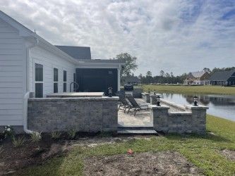 Backyard patio with stone walls, lounge chairs, and a small pond.