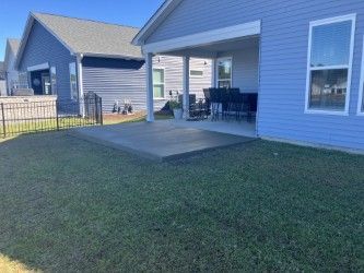 Backyard with a concrete patio, grass lawn, and blue house.