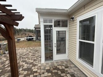 Glass door and windows on a beige house, next to a brick patio.