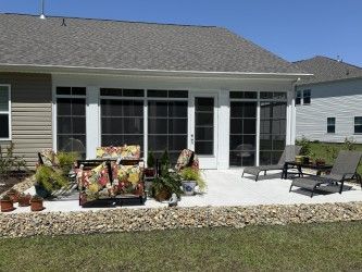 Patio with screen enclosure, outdoor furniture, plants, and gravel border.