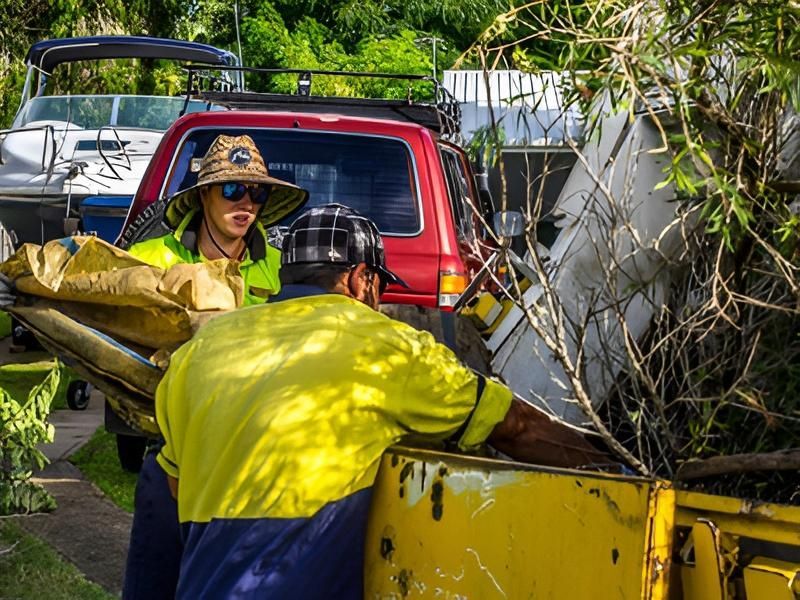 Men in Work Clothes Loading Debris Into a Yellow Truck — Bobs Bags & Bins in Mackay, QLD
