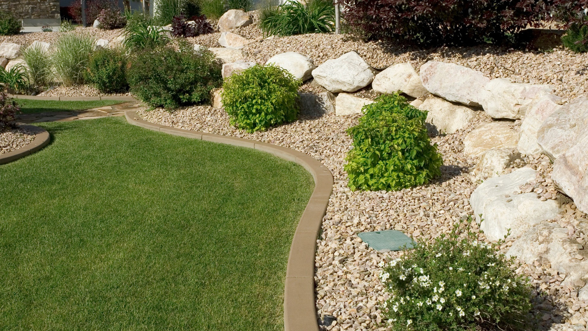 A lush green lawn surrounded by rocks and bushes.