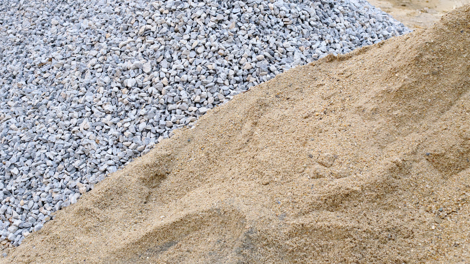 A pile of gravel next to a pile of sand.