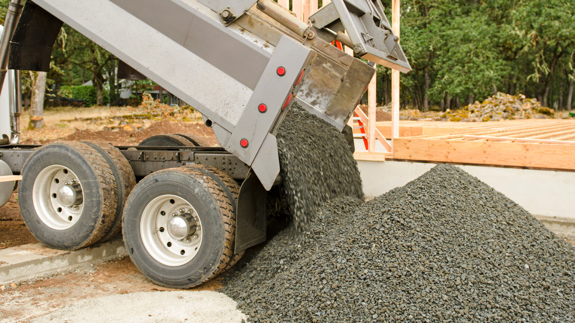 A dump truck is dumping gravel on a construction site.