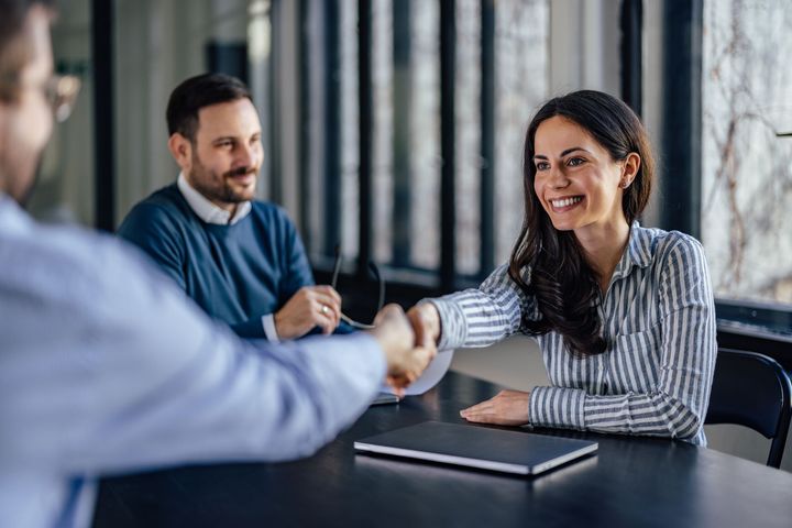 An image of three people with two people shaking hands