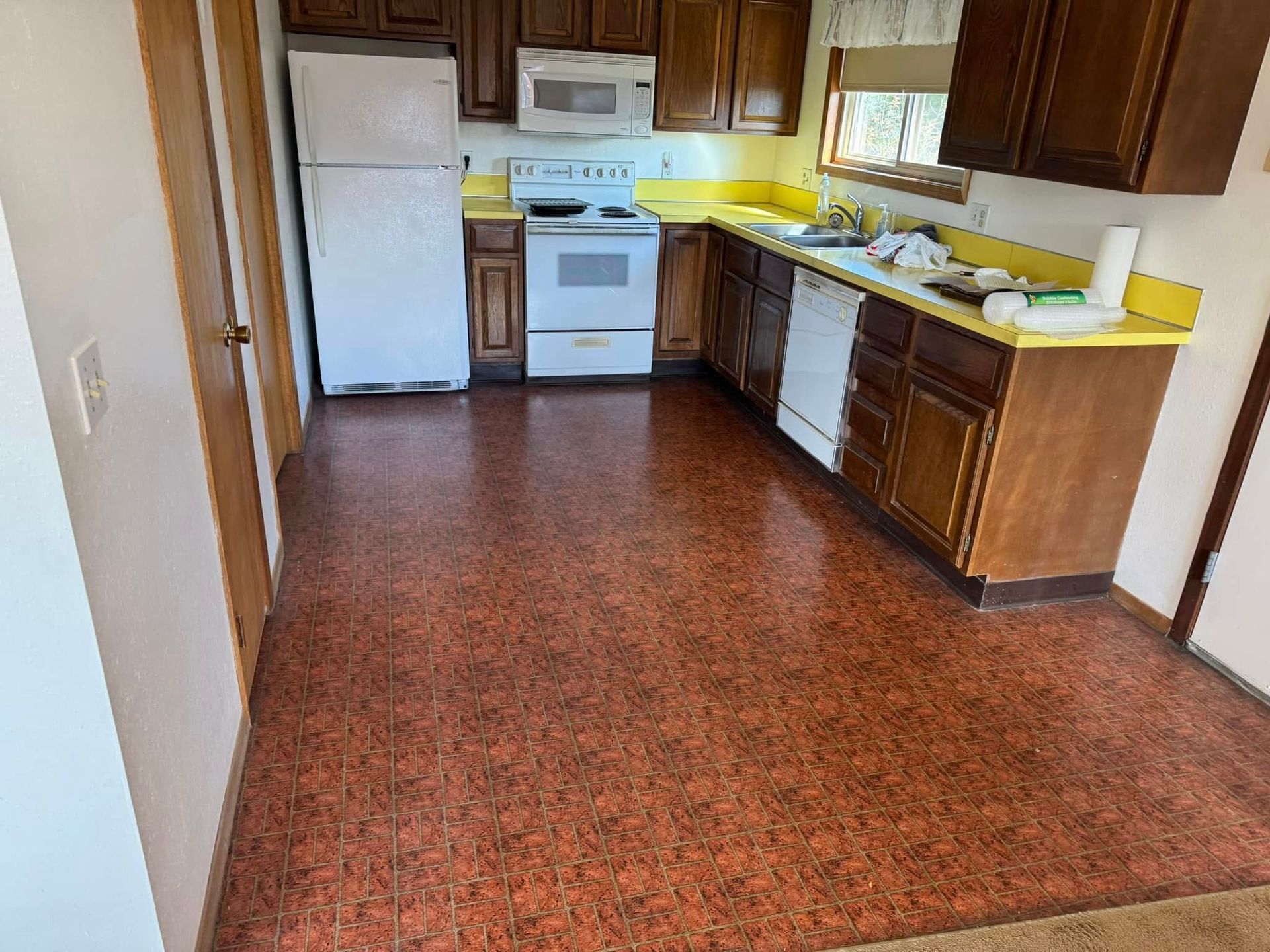 A kitchen with a stove , refrigerator , sink , and microwave.