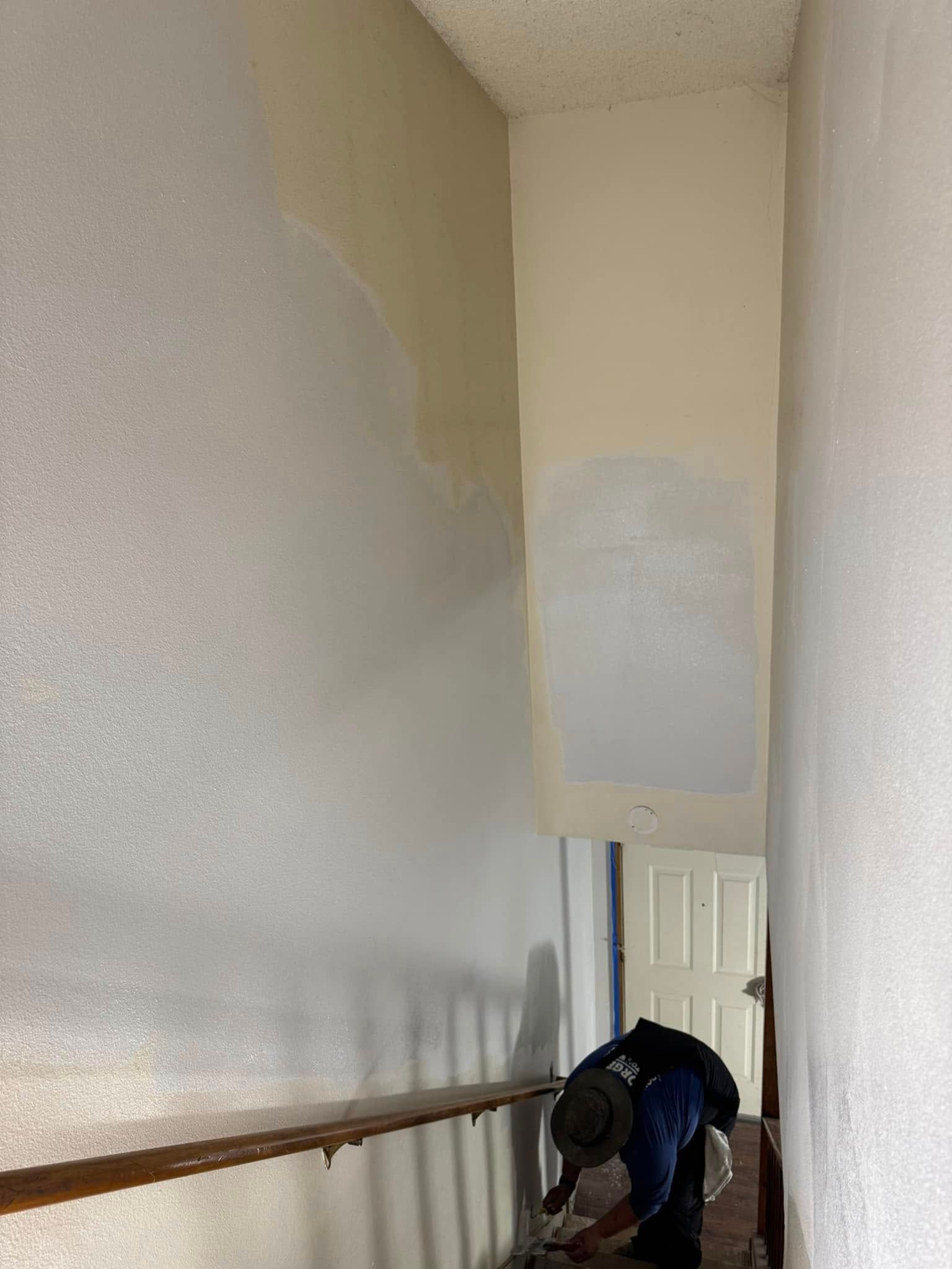A man is painting a wall in a hallway.