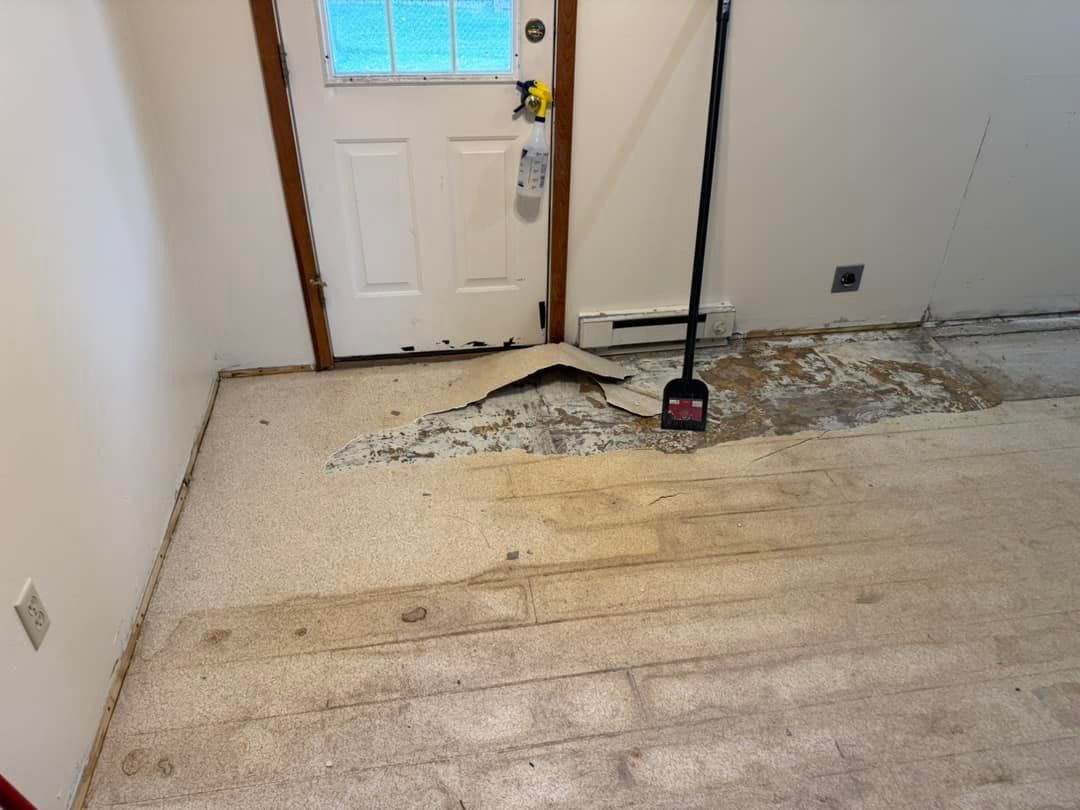 A room with a door and a broom on the floor.