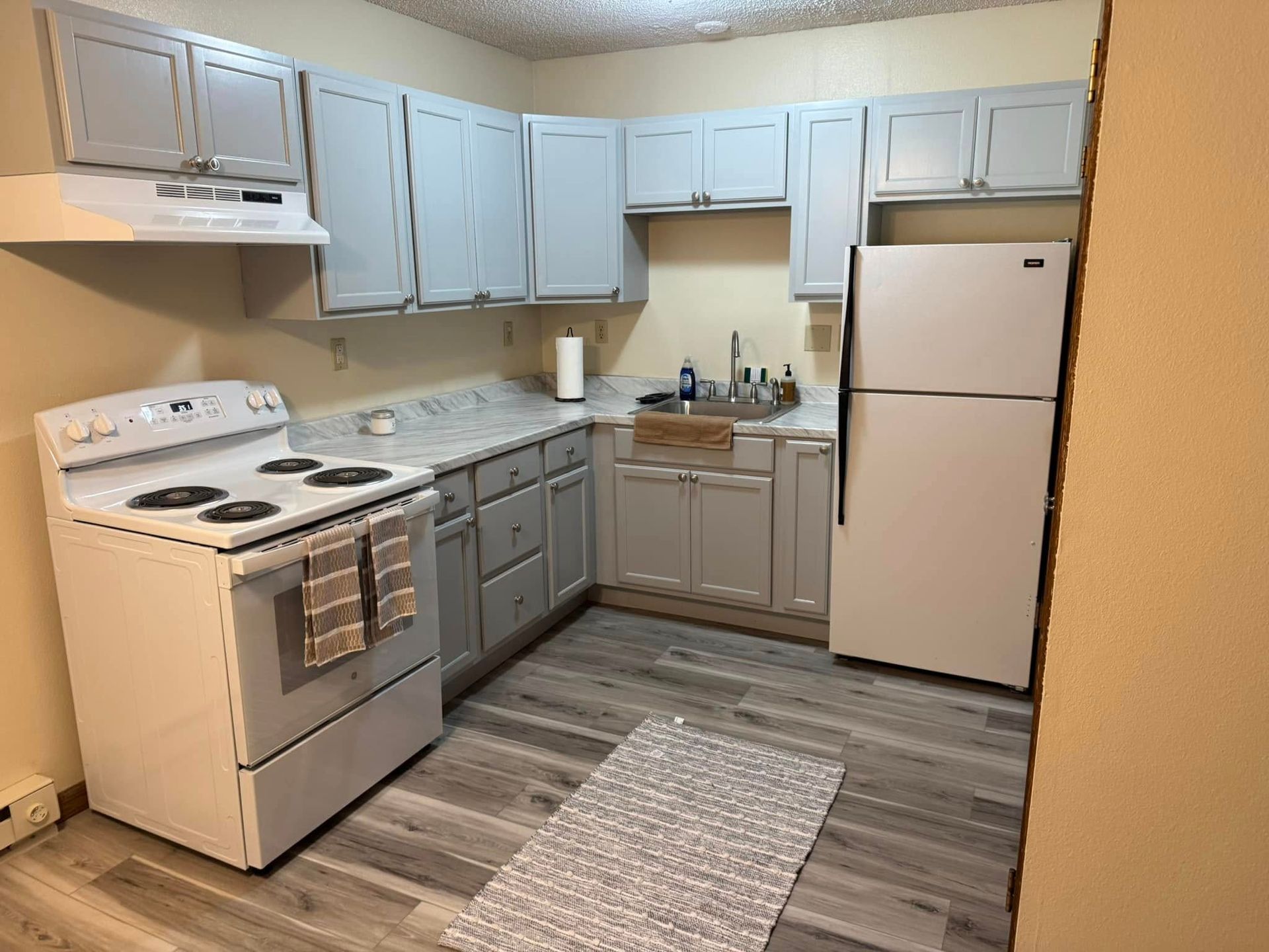 A kitchen with a stove , refrigerator , and sink.