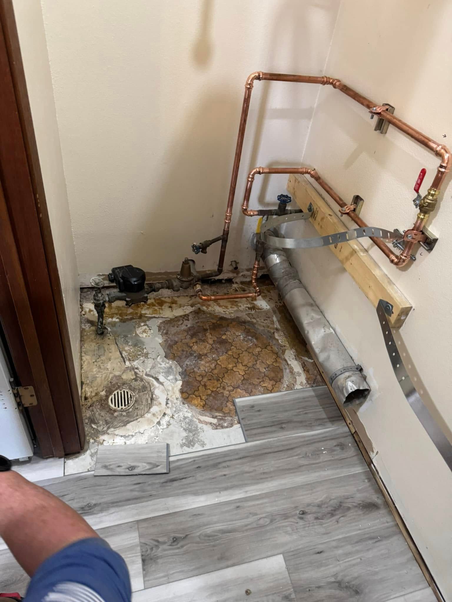 A person is standing in a room with a lot of pipes on the floor.