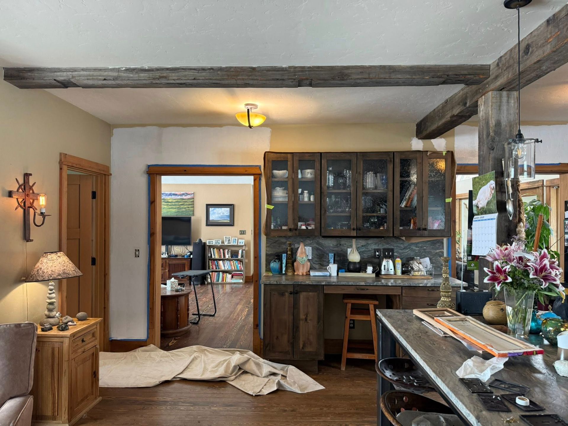 A living room with wooden cabinets , a table and a lamp.