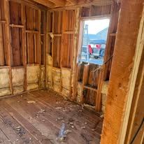 A room with wooden walls and a wooden floor in a house under construction.