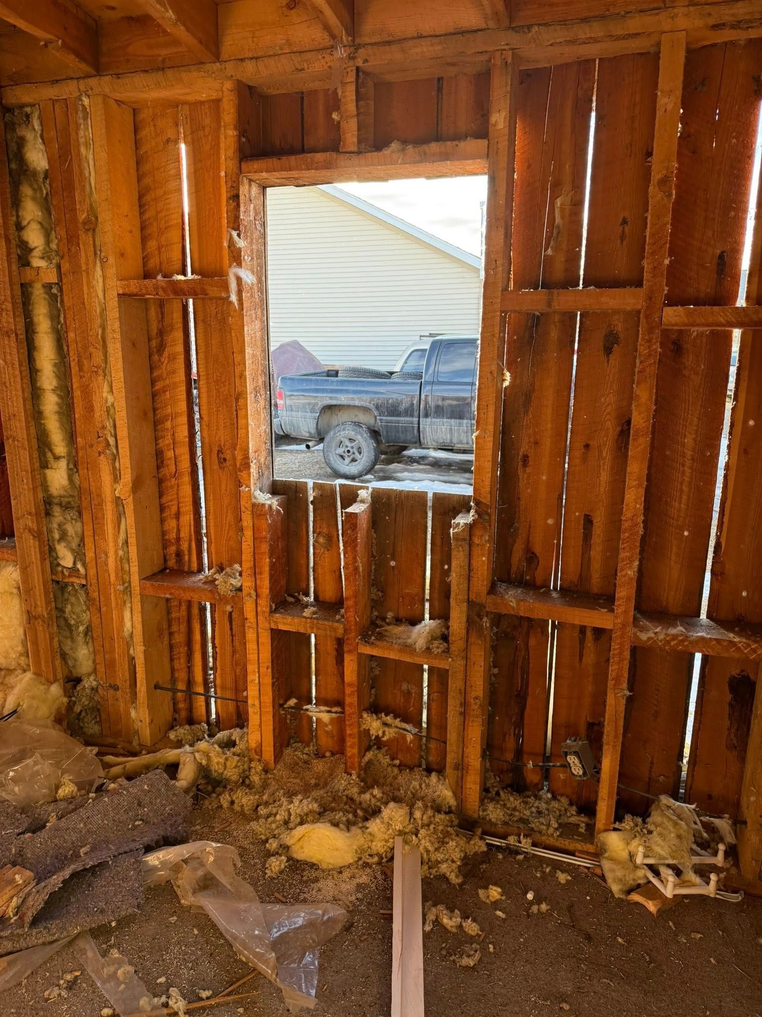 A room with a wooden wall and a window with a truck parked in the background.