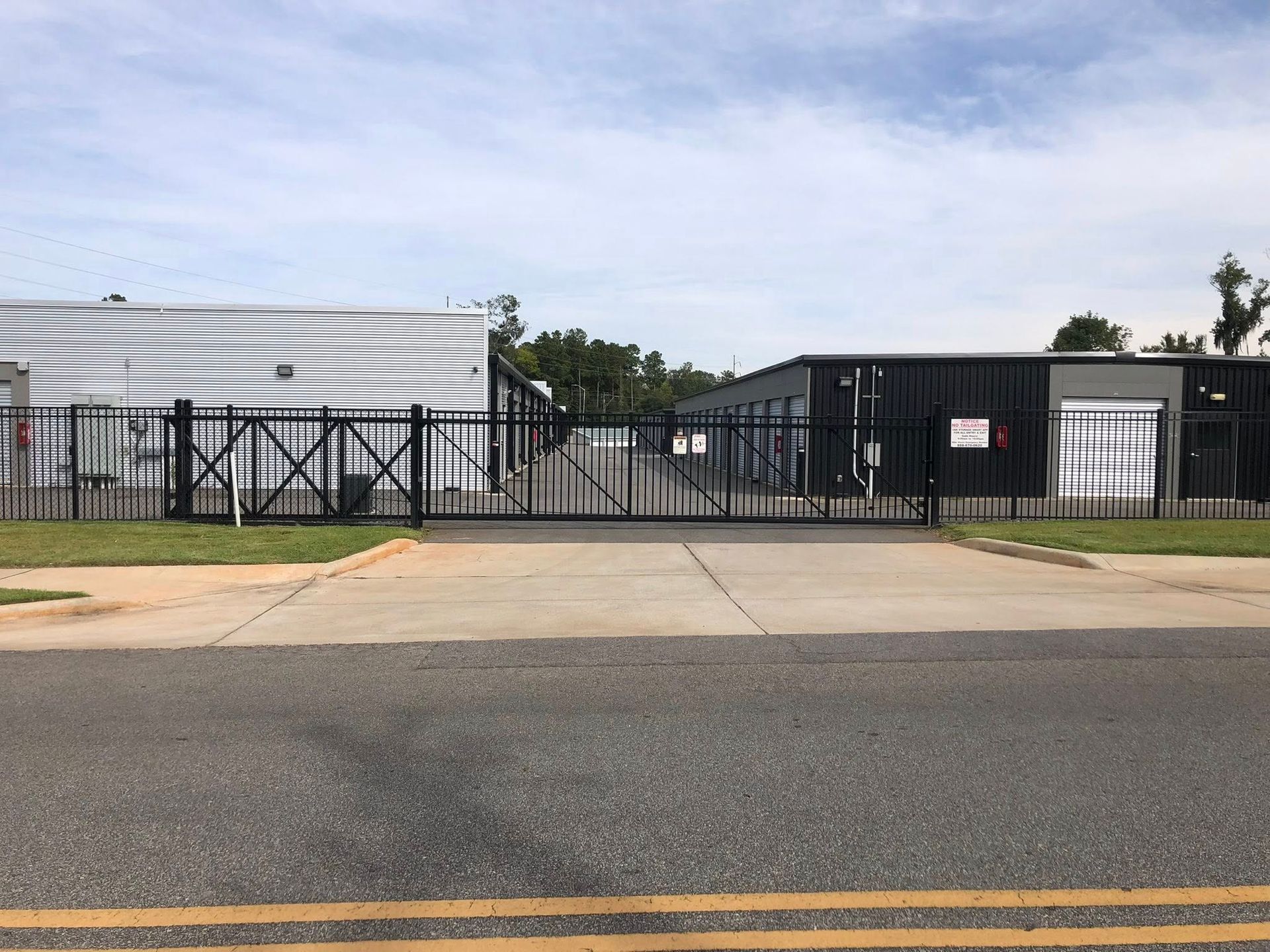Chain-link fence in foreground; warehouse loading docks and trucks blurred in background.
