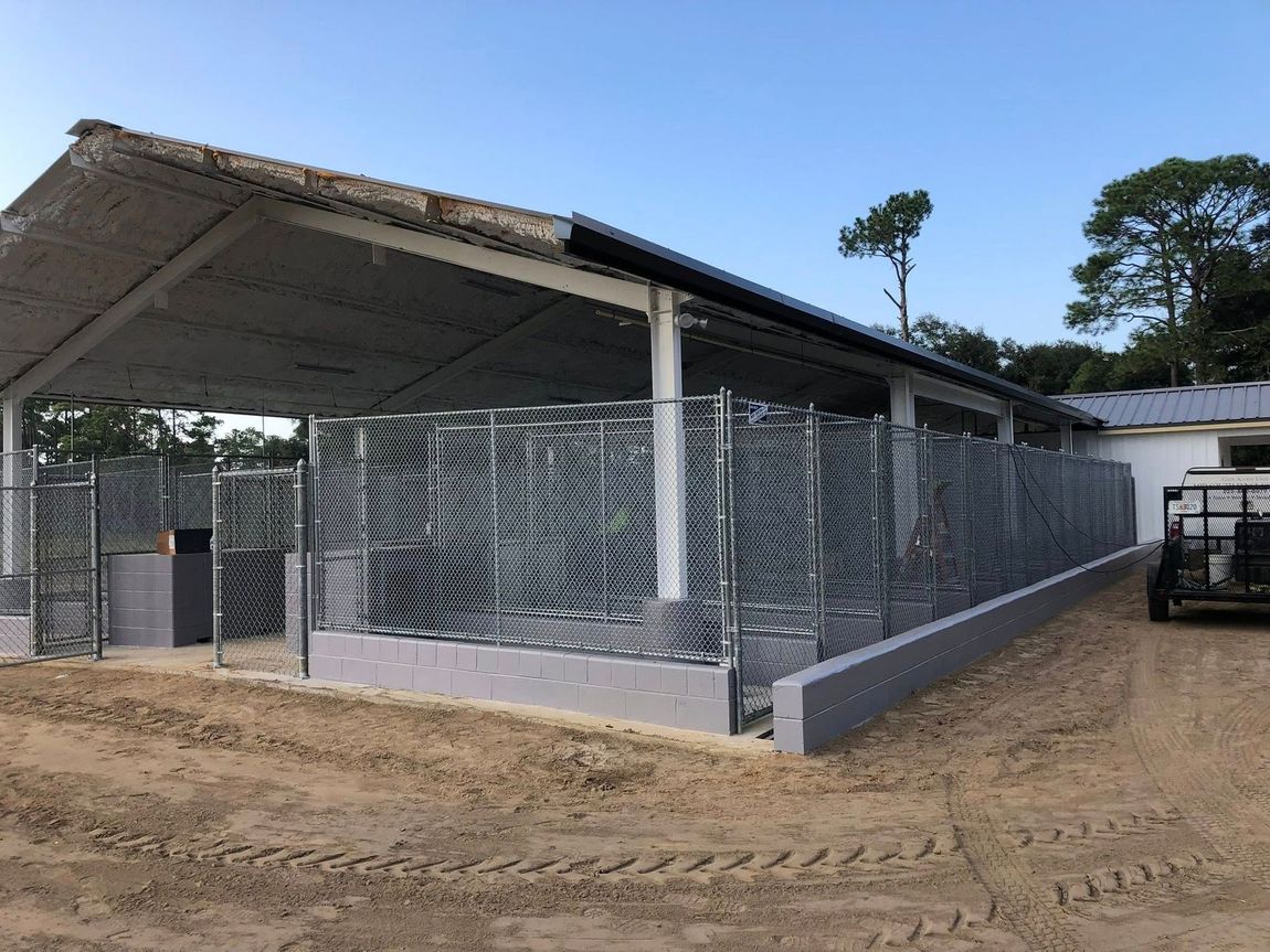 Wooden dog houses inside wire enclosures, set against a green background. Wooden dog houses inside wire enclosures, set against a green background.
