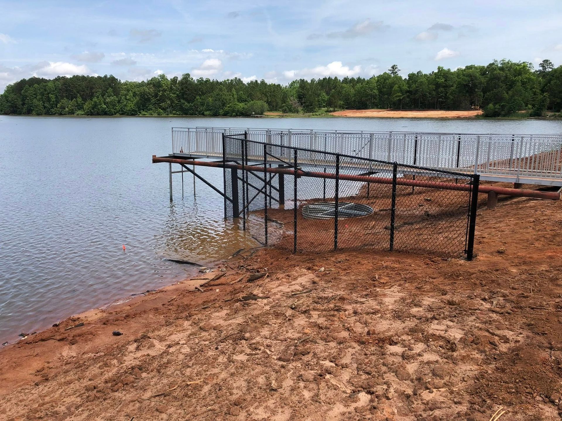 Blue-framed chain-link fence bordering a baseball field, viewed from a covered concrete shelter under a blue roof. Blue-framed chain-link fence bordering a baseball field, viewed from a covered concrete shelter under a blue roof.
