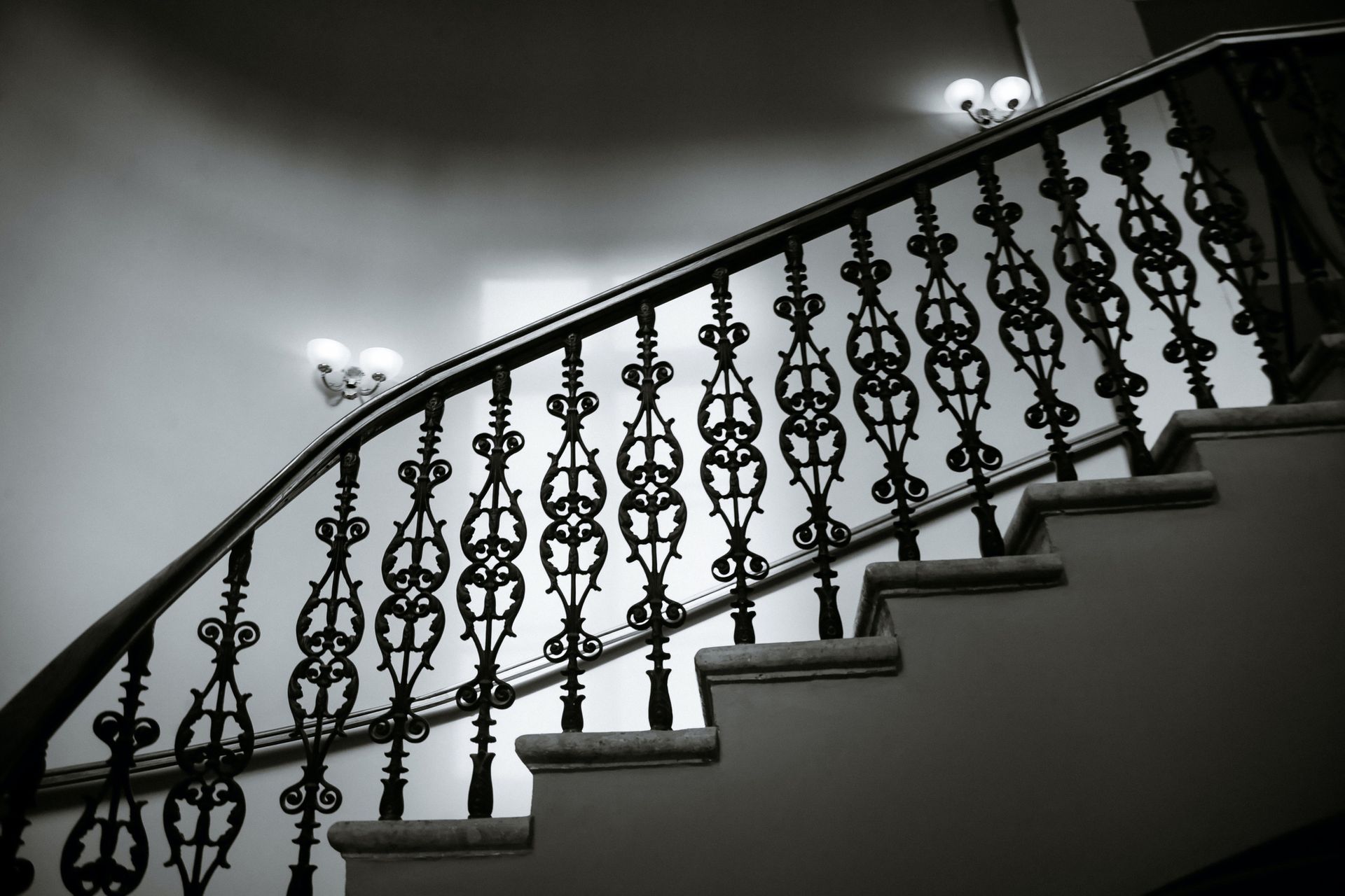 Black and white photo of a staircase with ornate iron railing. Black and white photo of a staircase with ornate iron railing.