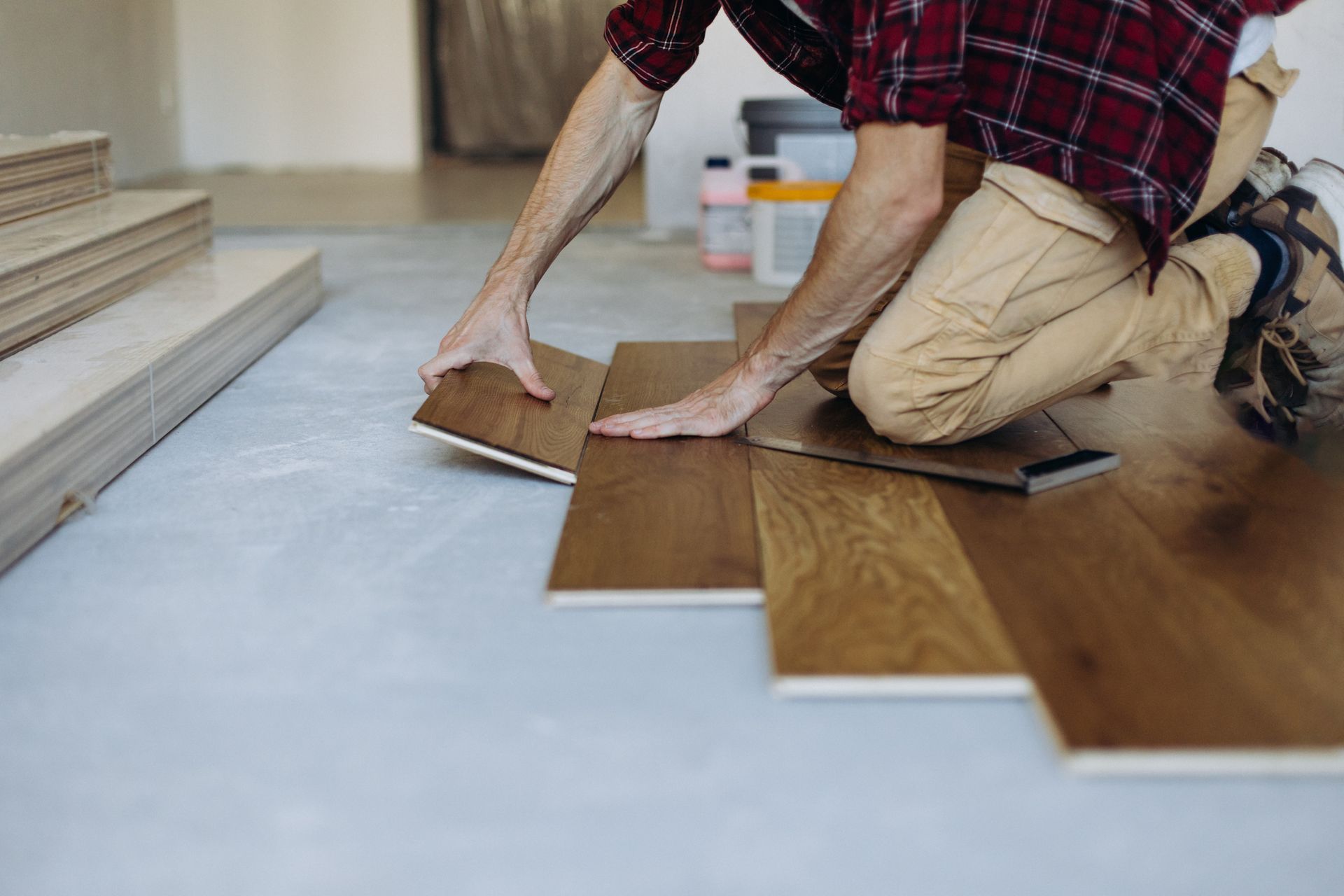 Hardwood flooring contractor installing wooden planks of a parquet floor in a home.