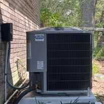 An air conditioning unit attached to a brick wall outdoors.