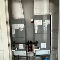 Two HVAC units in a utility closet, with ductwork, wiring, and a fire alarm.