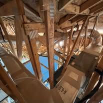 Wooden attic structure with ductwork and insulation.