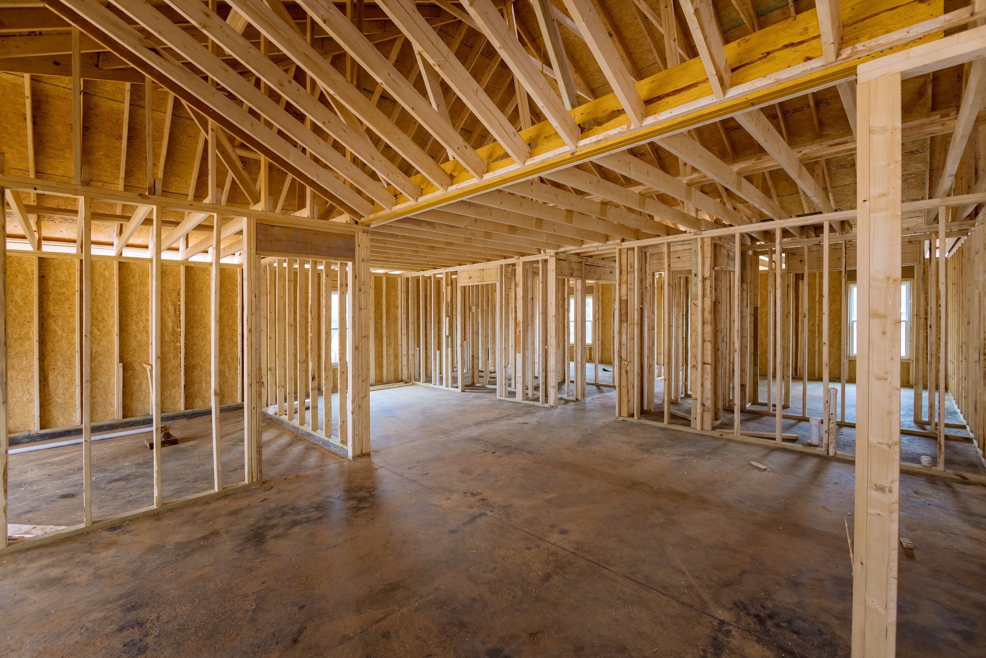 Interior framing of a house under construction, showing walls, ceiling, and roof supports.