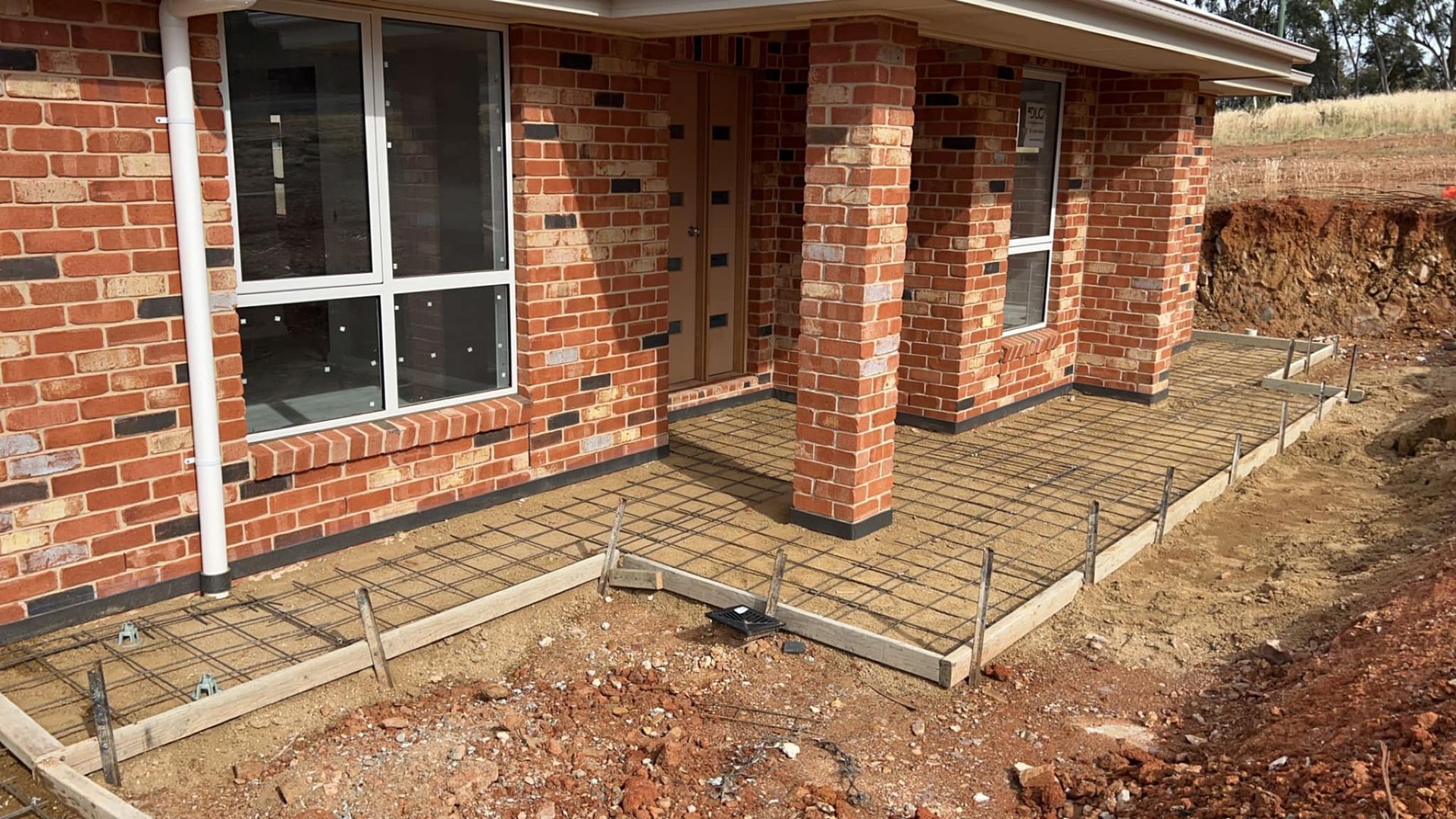 A Brick House With a Concrete Walkway in Front of It — Brycey's Concreting In Frederickton, NSW