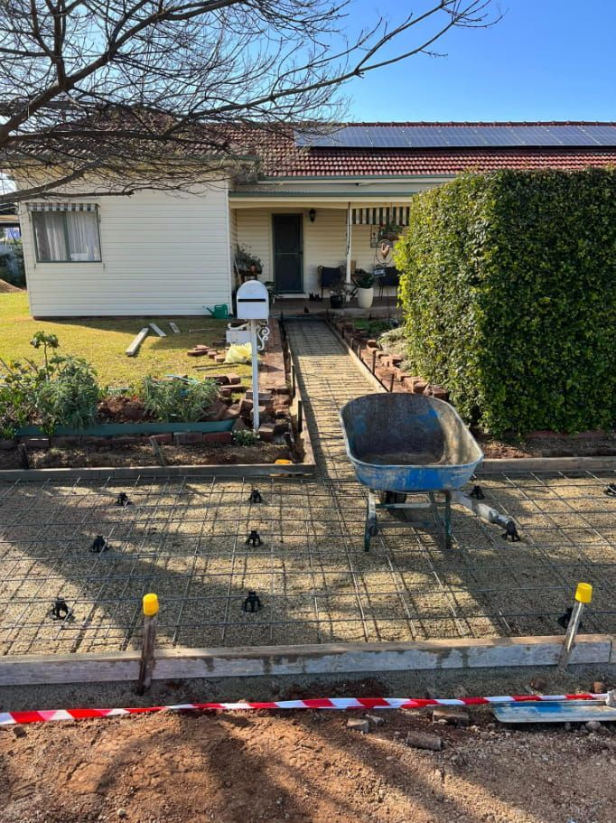 A Wheelbarrow is Sitting in Front of a House — Brycey's Concreting In Frederickton, NSW