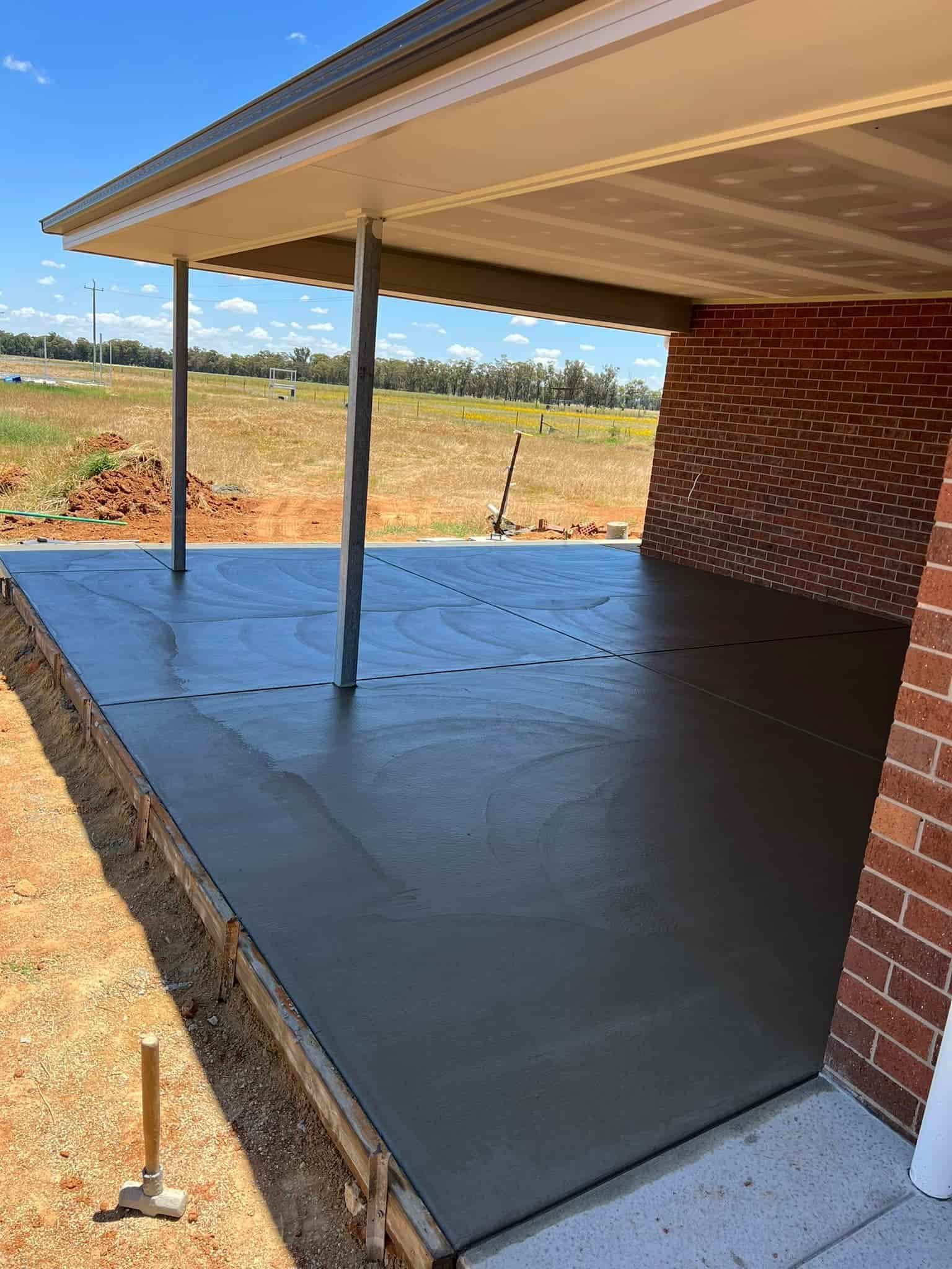 A Brick House With a Concrete Porch Underneath It — Brycey's Concreting In Frederickton, NSW