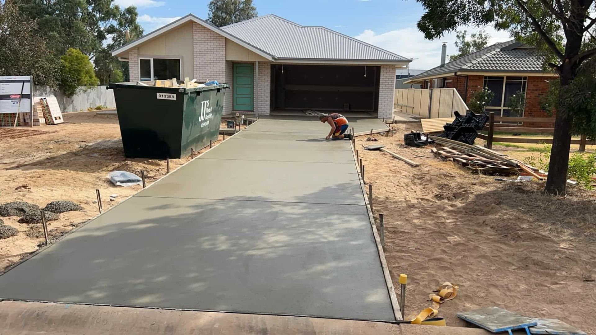 A Concrete Driveway Leading to a House With a Garage Door Open — Brycey's Concreting In Frederickton, NSW