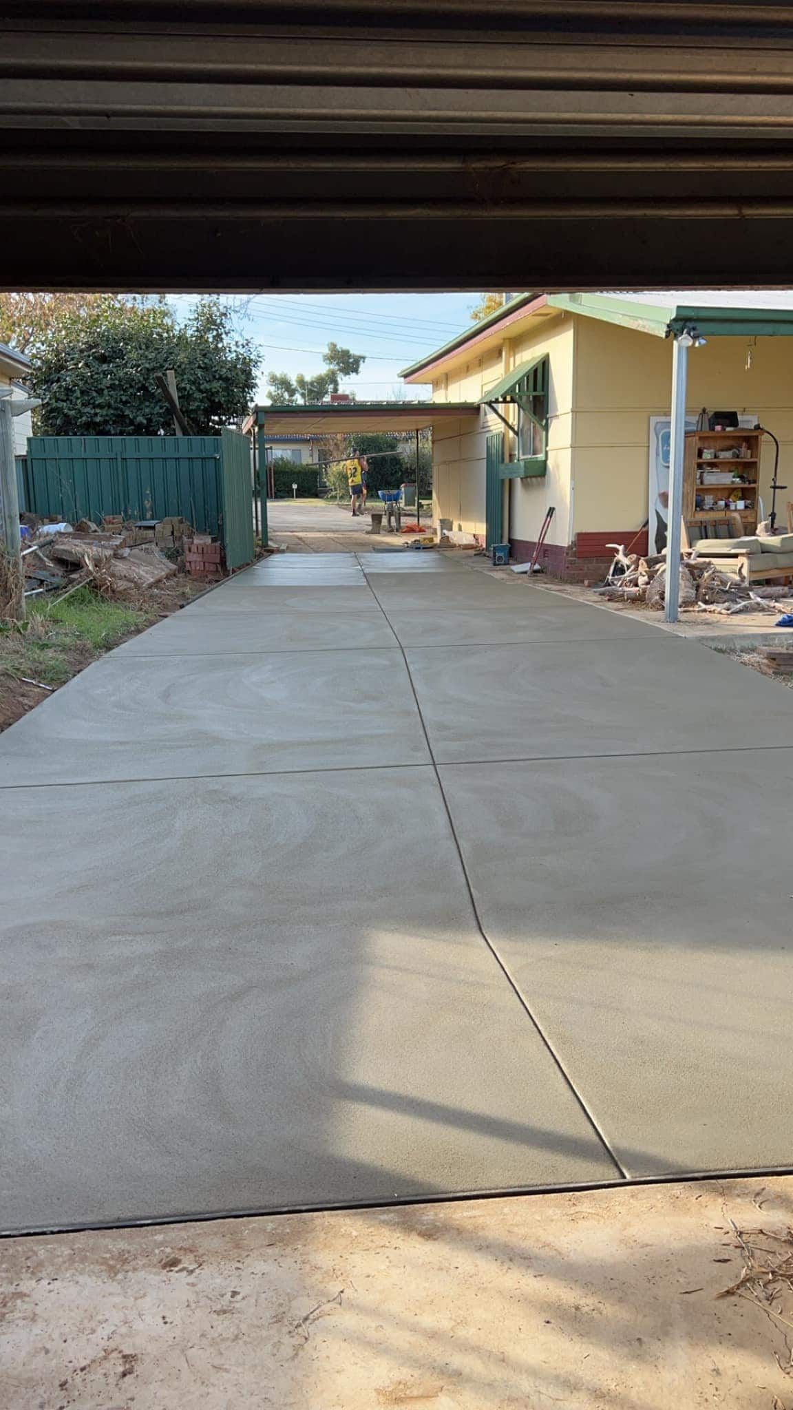 A Concrete Driveway Leading to a House With a Garage Door Open — Brycey's Concreting In Frederickton, NSW