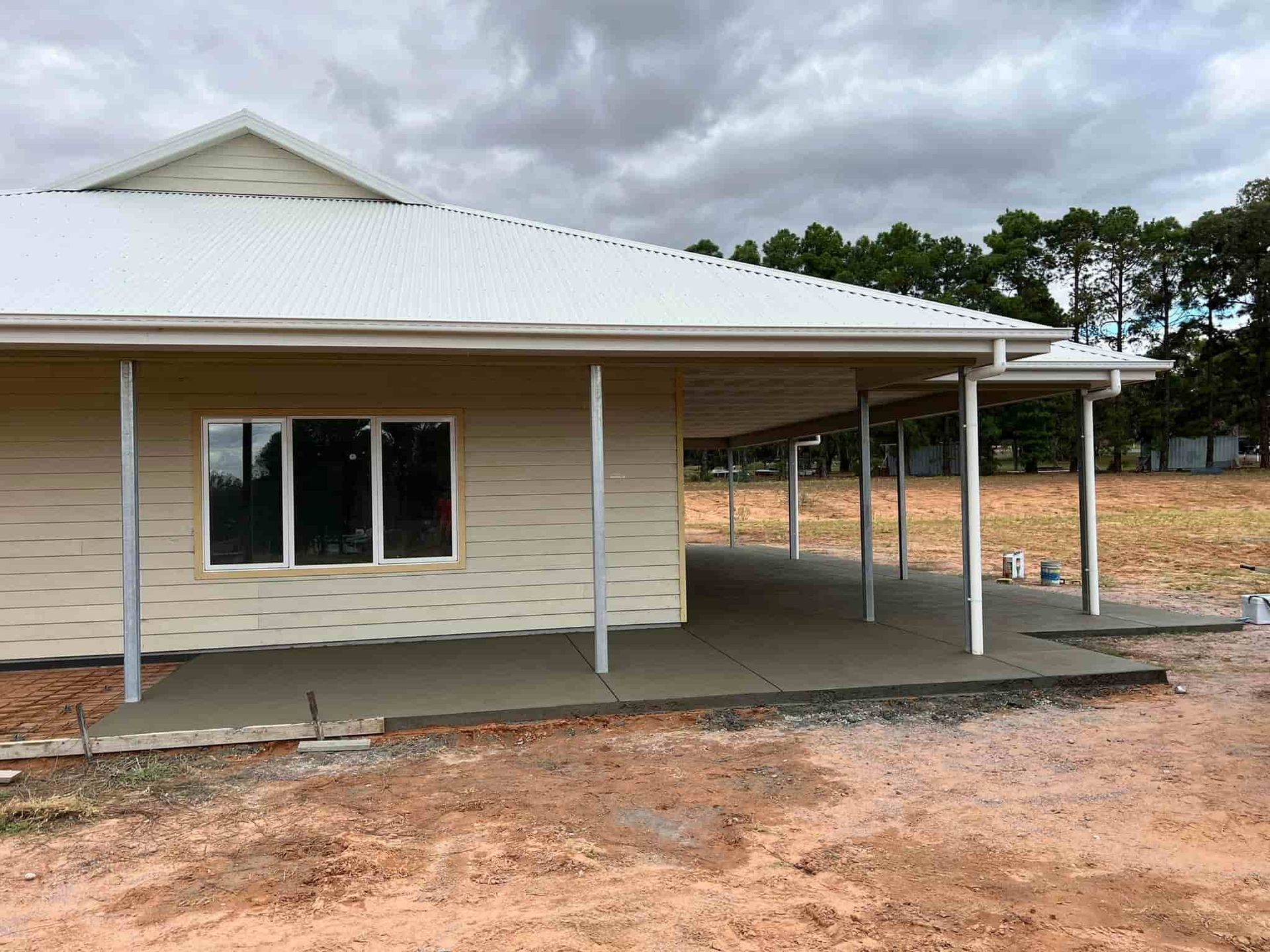 A House With a Porch and a White Roof is Being Built in a Dirt Field — Brycey's Concreting In Frederickton, NSW
