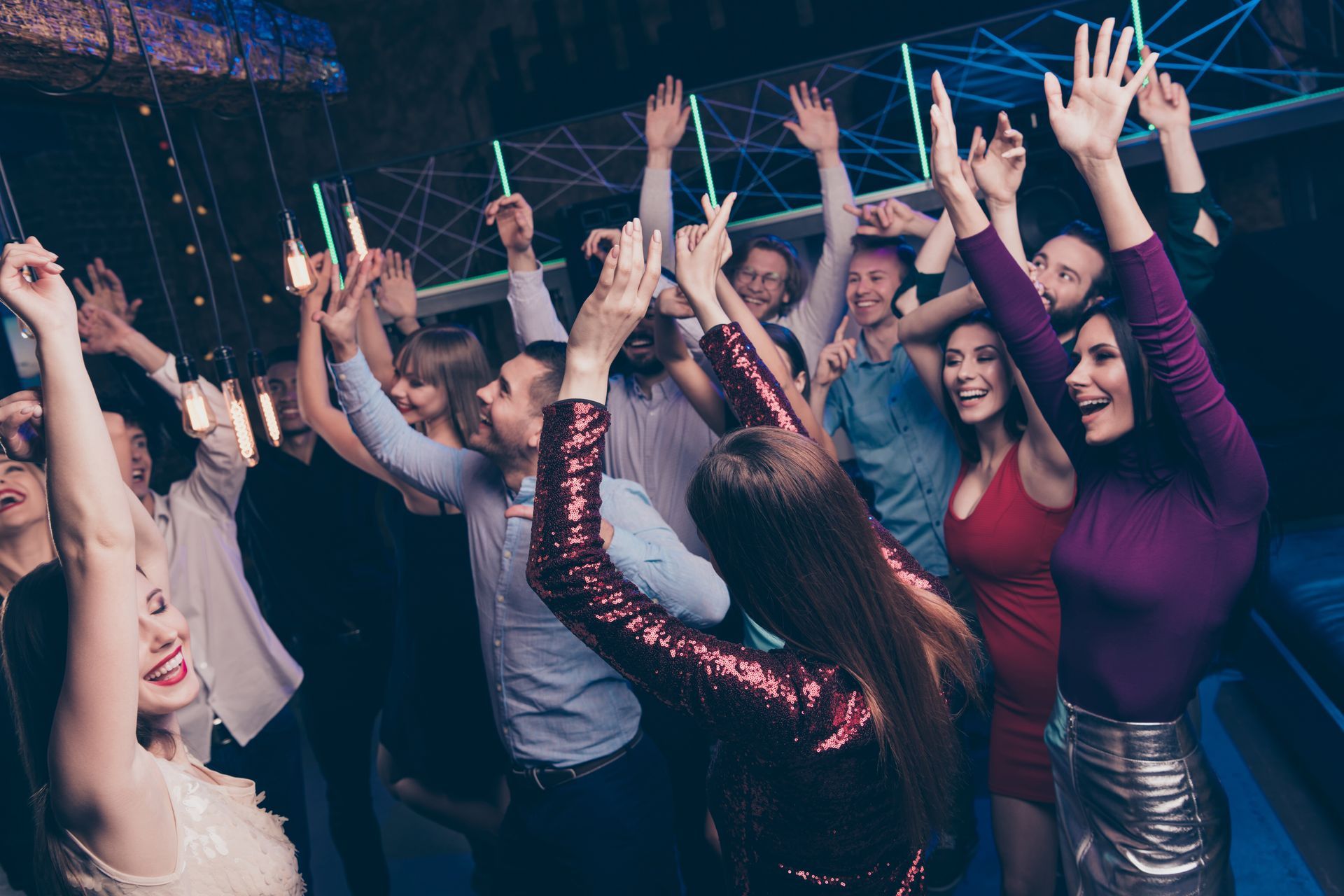 A group of adults dancing at a party with hands raised