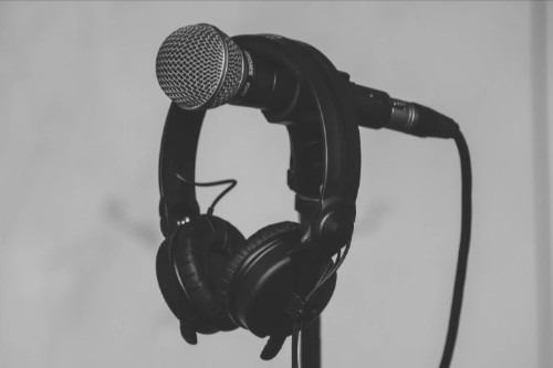 Microphone with headphones hanging over the top of them