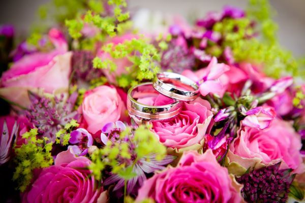 Two wedding rings lying on top of a bouquet of roses