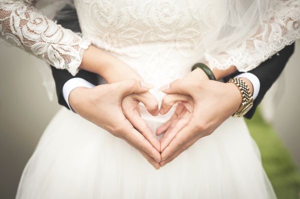 A view of the hands of a newly married couple making a heart shape out of their hands