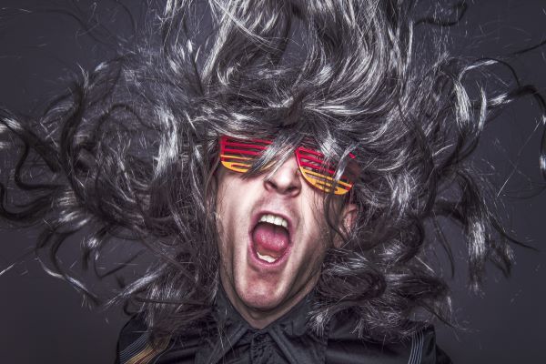 A young man yelling, with long, thick grey hair flowing upward