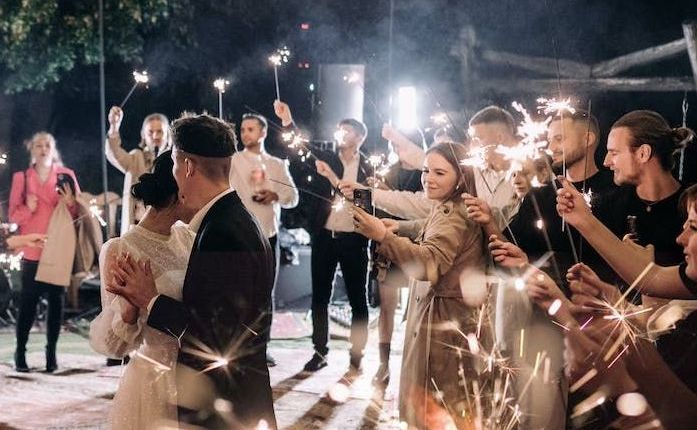 A newlywed couple dances on the dance floor with friends surrounding them