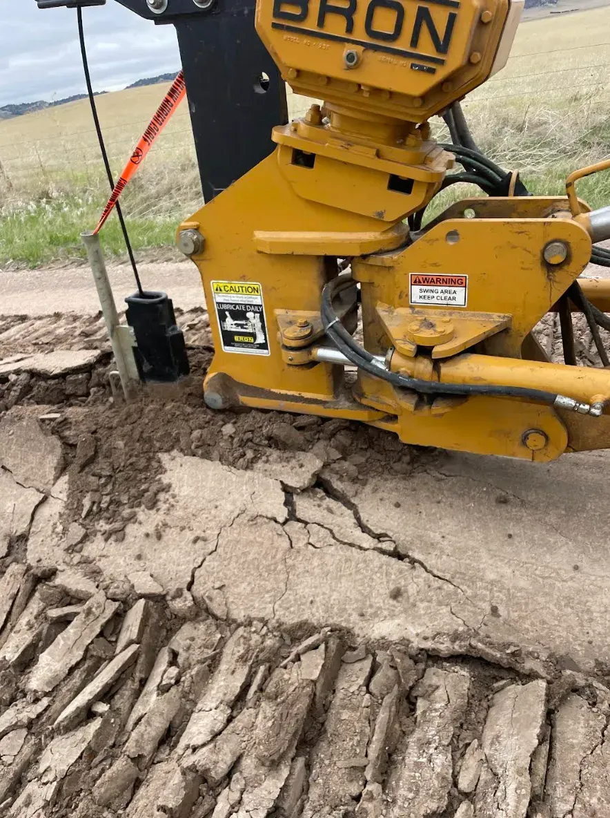 Yellow hydraulic hammer breaking up asphalt road.